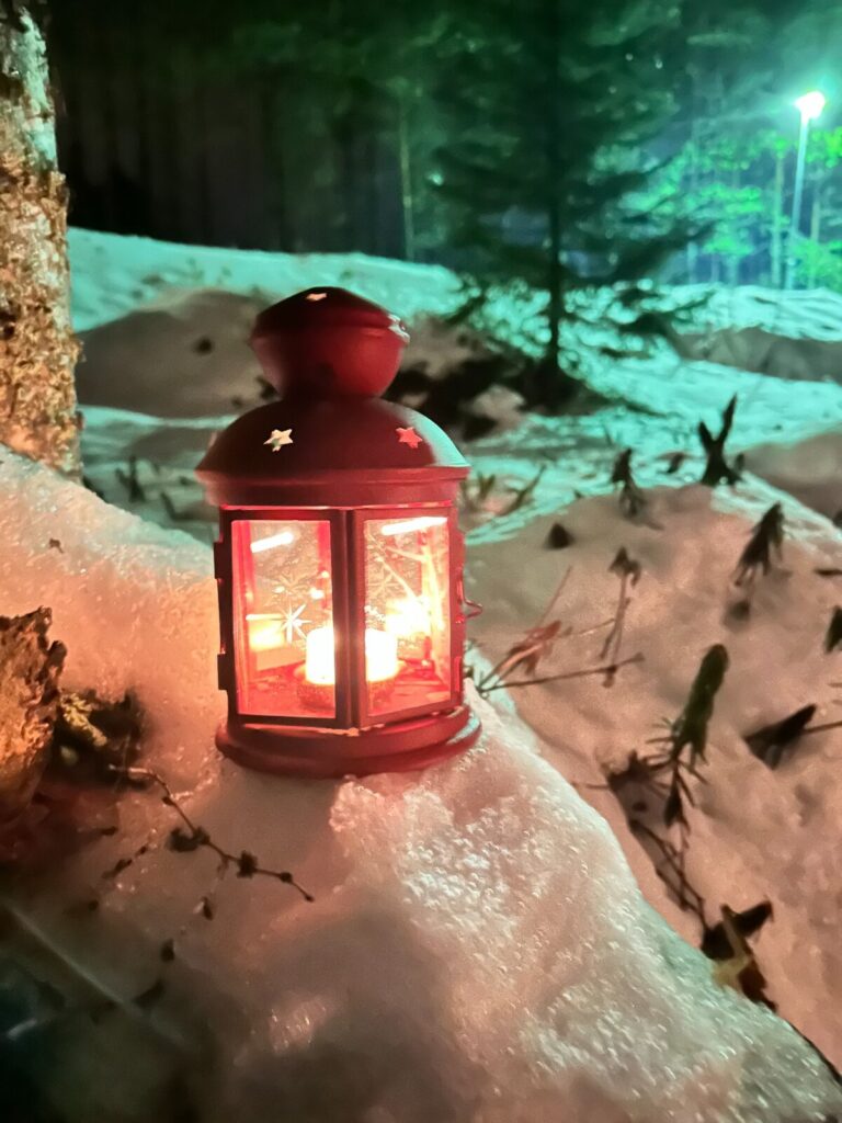 Warm lantern beside a snowy forest path in Vuokatti