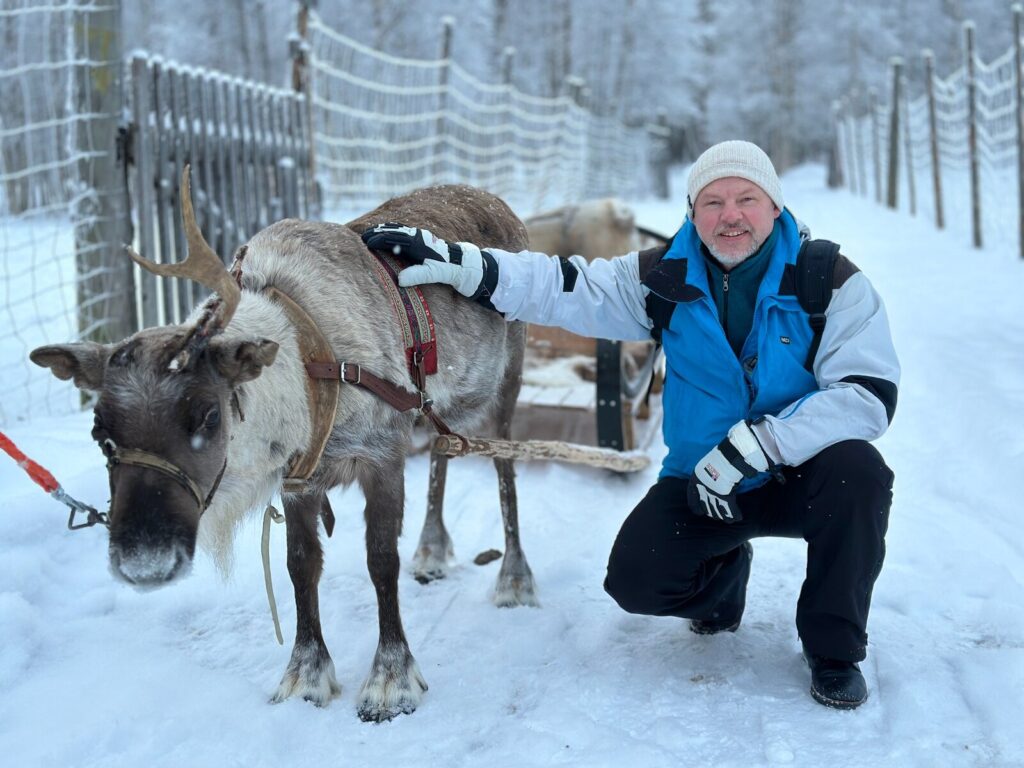 Guest meeting a reindeer at a snowy farm in Vuokatti