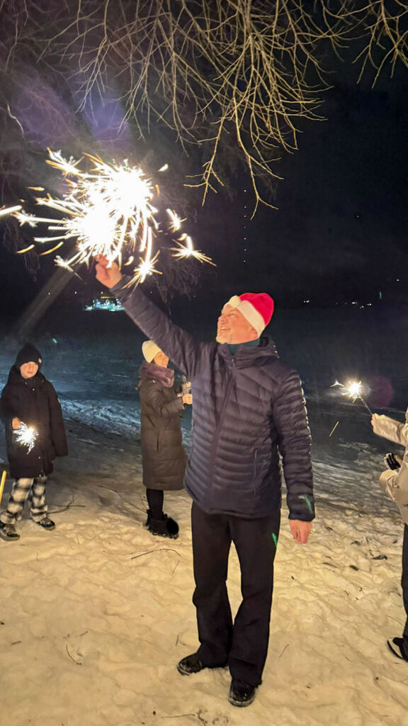 Guest holding a bright sparkler during a New Year celebration in Vuokatti
