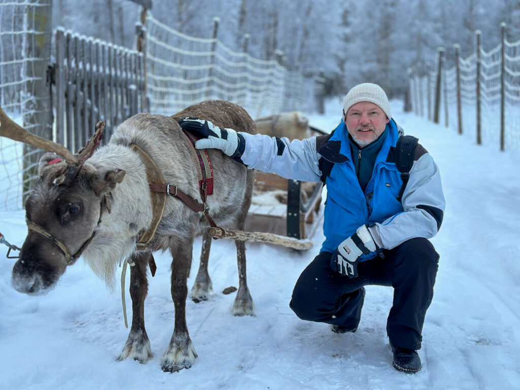 Guest meeting a reindeer at a snowy farm near Vuokatti