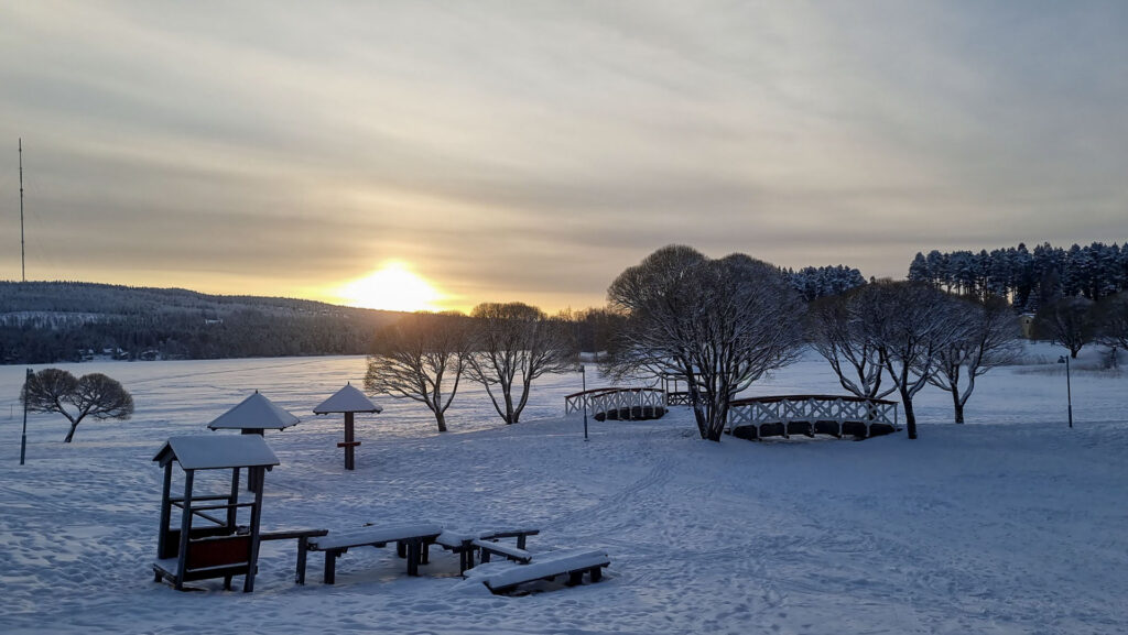 Soft sunset light over a snow-covered lakeshore in Vuokatti